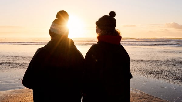 2 women walking on the beach on a sunny, winters day